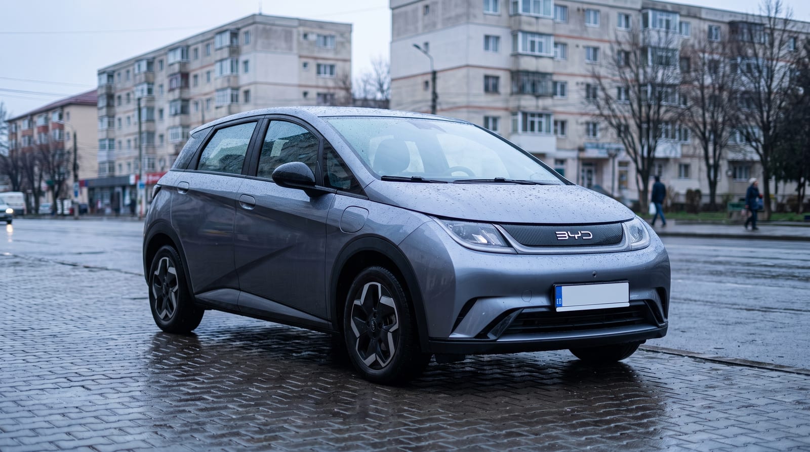 Hatchback compact BYD Dolphin G văzut din trei sferturi față, pe fundal urban, lumină de zi