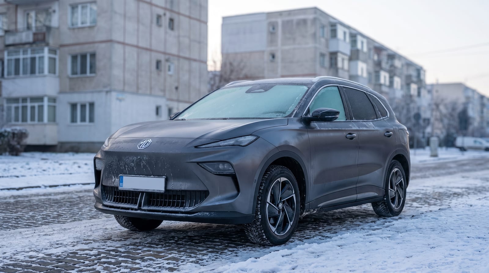 SUV electric MG S5 parcat iarna pe o stradă dintre blocuri, cu zăpadă pe carosabil și brumă pe parbriz